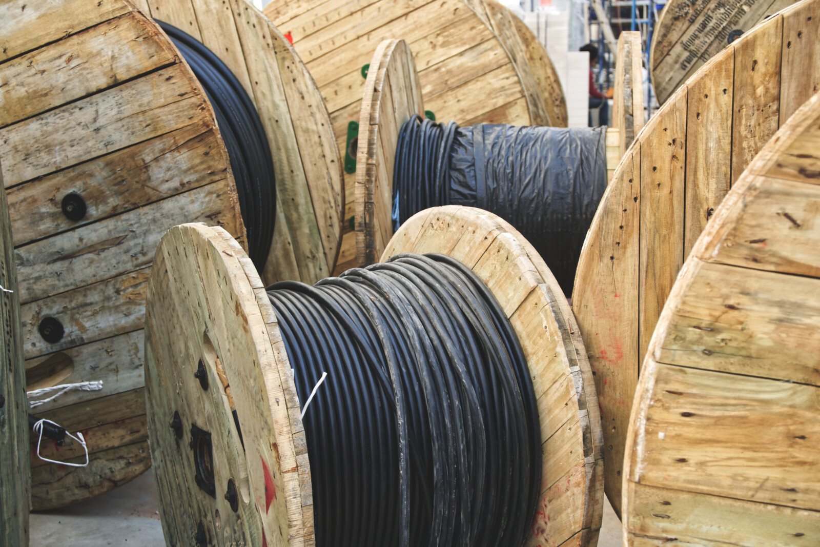Wooden spools with black cables in a factory representing surplus wire reels and spool inventory ready for resale